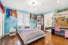 Hardwood flooring, multi-tier decorative ceiling light fixture, plantation shutters, built-in floor-to-ceiling cabinetry, and integrated desk with ove