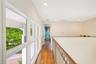 Hallway featuring wood-finish flooring, metal railing with wood-finish handrail, recessed lighting, and large windows