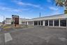 Commercial exterior featuring flat roof architecture, multiple floor-to-ceiling windows, and a paved parking lot with painted wheel stops