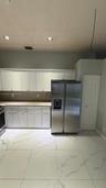 Kitchen featuring white cabinetry, stone-surface countertops, large-format tile flooring, stainless steel side-by-side refrigerator, and recessed ceil