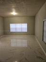 Interior room featuring large-format tile flooring with a veined pattern, neutral-toned wall paint, and windows with integrated blinds