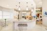 Kitchen featuring a waterfall-edge stone island, geometric pendant lighting, built-in double ovens, and professional-grade stainless steel refrigerato