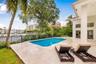 Outdoor terrace featuring natural stone tile flooring, a rectangular swimming pool with integrated spa, and a metal perimeter fence