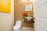 Mosaic tile wall accent, wall-mounted floating wood vanity, white vessel sink with wall-mounted faucet, and square frameless mirror