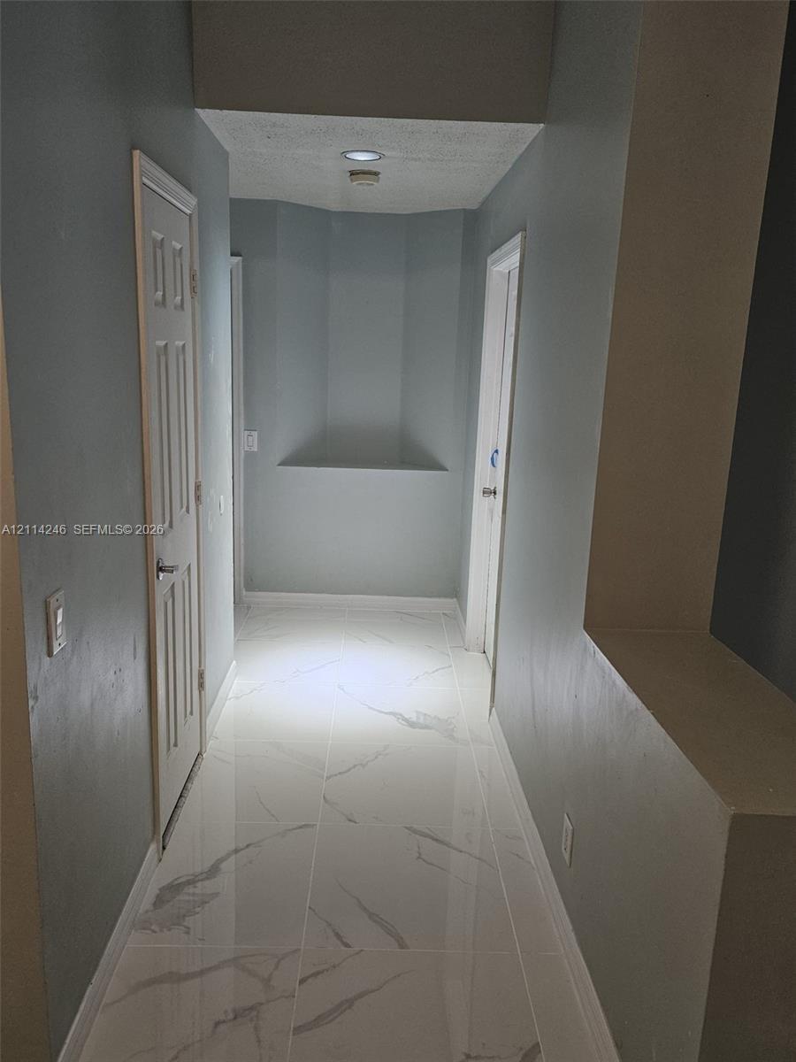 Hallway featuring large-format tile flooring with a veined finish, recessed wall niches, and paneled interior doors