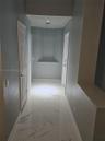 Hallway featuring large-format tile flooring with a veined finish, recessed wall niches, and paneled interior doors