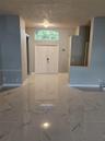 Entryway featuring large-format tile flooring with a neutral veined pattern, double front doors, and a semi-circular transom window
