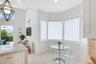 High-ceilinged room featuring a bay window, light-toned tile flooring, a geometric pendant light fixture, and a kitchen island with a stone-finish cou