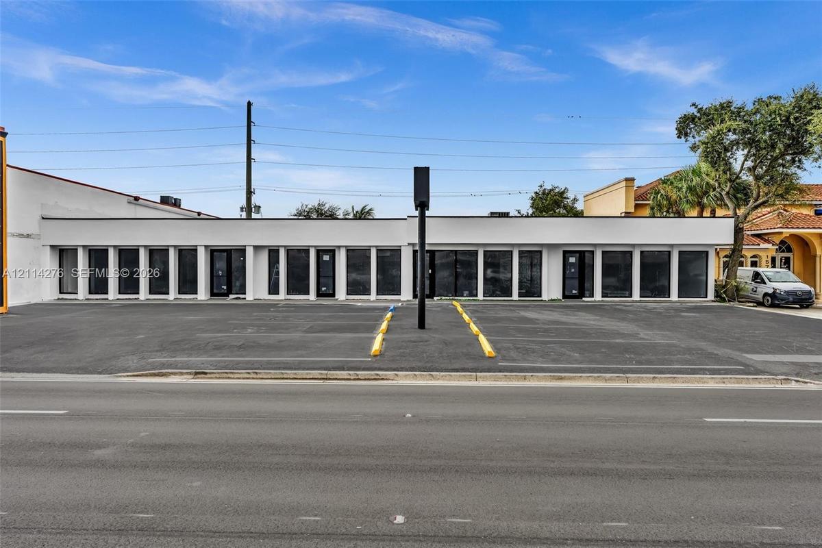 Commercial property featuring an expansive asphalt parking lot with dedicated parking blocks, a flat-roof exterior facade, and floor-to-ceiling glass 