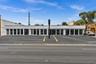 Commercial property featuring an expansive asphalt parking lot with dedicated parking blocks, a flat-roof exterior facade, and floor-to-ceiling glass 