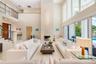 Double-height living area featuring a floor-to-ceiling stone fireplace, expansive glass wall panels, a mezzanine balcony with metal railing, and polis