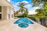 Outdoor living space featuring a tiled pool deck, a swimming pool with an integrated spa, and metal perimeter fencing