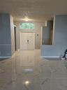 Double entry doors featuring a decorative arched transom window, finished with high-gloss large-format tile flooring and neutral-toned wall paint