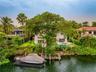 Waterfront property featuring a private boat dock, swimming pool, concrete patio, and mature trees