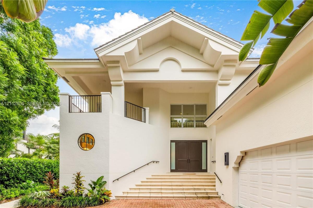 Architectural exterior featuring a vaulted gabled roofline, decorative corbels, a private second-story balcony with metal railings, a circular accent 