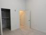 High-ceilinged room featuring light-toned wood-finish flooring, white walls, built-in closet shelving, and solid-core doors with brushed-metal hardwar