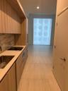 Kitchen featuring wood-finish cabinetry, stone-surface countertops, full-height decorative backsplash, stainless steel sink, and large-format tile flo