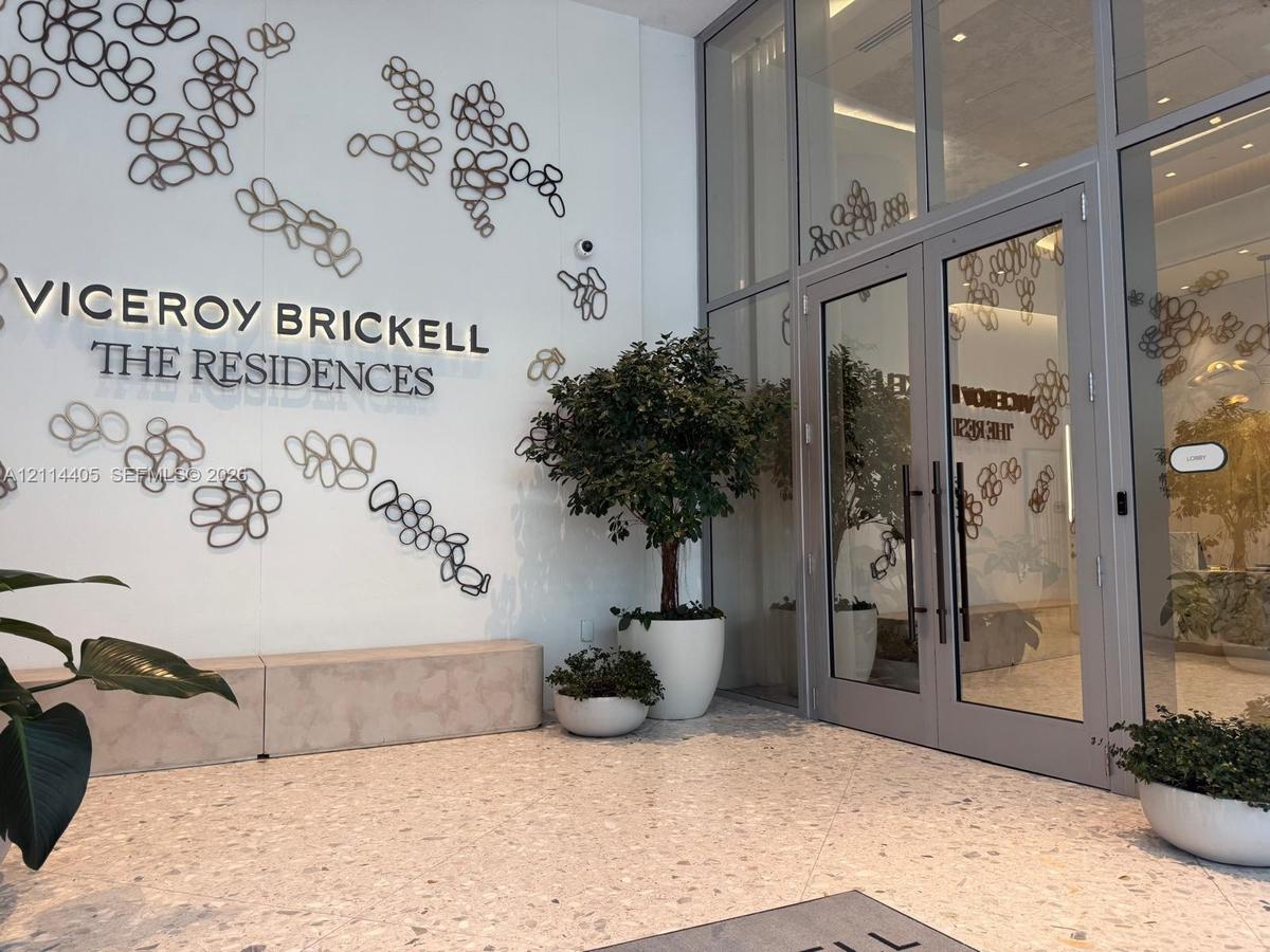 Entrance featuring floor-to-ceiling glass paneling, double-door entryway, terrazzo flooring, and decorative metallic wall art