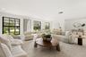 Open-concept living space featuring expansive windows with black mullions, recessed ceiling lighting, and neutral-toned wall-to-wall carpeting