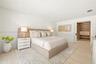 Neutral-toned room featuring light-toned wood-finish flooring, recessed lighting, and a walk-in closet with built-in cabinetry accessed by a sliding p