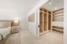 Walk-in closet featuring custom built-in cabinetry, integrated vertical lighting, polished drawers, open shelving, and a sliding door