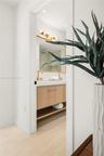 Floating vanity featuring wood-finish cabinetry, a white countertop with integrated double sinks, metallic hardware, and a minimalist-style vanity lig
