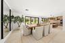 Open-concept interior featuring light-toned tile flooring, custom wood cabinetry, a built-in double wall oven, and sliding multi-panel glass doors