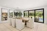 Open-concept interior featuring large-format tile flooring, recessed lighting, expansive multi-panel sliding glass doors, and three floor-to-ceiling w