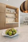 Built-in wood-finish cabinetry featuring integrated recessed lighting, stone-surface countertop, open shelving, and brushed brass hardware
