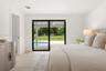 Light-filled interior featuring sliding glass doors with black frames, neutral stone-finish flooring, and recessed lighting