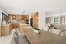Custom wood cabinetry with integrated lighting, stone countertops, stainless steel built-in double ovens, recessed lighting, and large-format tile flo
