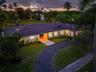 Single-story residence featuring a tile roof, board-and-batten siding, a curved asphalt driveway, and expansive lawn landscaping