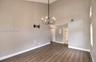 High-vaulted ceilings, dark wood-finish flooring, and a prominent six-light chandelier featuring a matte black finish