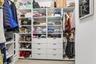 Custom walk-in closet featuring floor-to-ceiling white shelving, integrated hanging rods, eight pull-out storage drawers, and sleek metal hardware