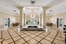 Grand lobby featuring polished stone flooring with geometric tile inlay, a central tiered water feature, soaring architectural pillars, recessed tray 