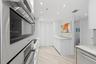 Kitchen featuring integrated wall ovens, white cabinetry, solid surface countertops, recessed lighting, and wood-finish flooring