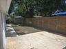 Rear outdoor space featuring a paved tile patio, a horizontal wood-slat privacy fence, and an integrated exterior storage structure