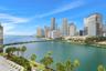 Panoramic waterfront outlook featuring the downtown skyline, a concrete bridge, and established palm trees