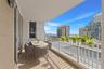 Covered balcony with neutral tile flooring, white metal railing, and sliding glass door access