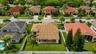 Aerial view of property featuring a multi-pitched clay tile roof, expansive rear lawn, white vinyl fencing, and covered patio