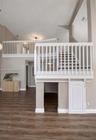 High-ceiling interior featuring wood-finish flooring, a white wooden staircase balustrade, and a lower-level built-in storage area with a sliding barn