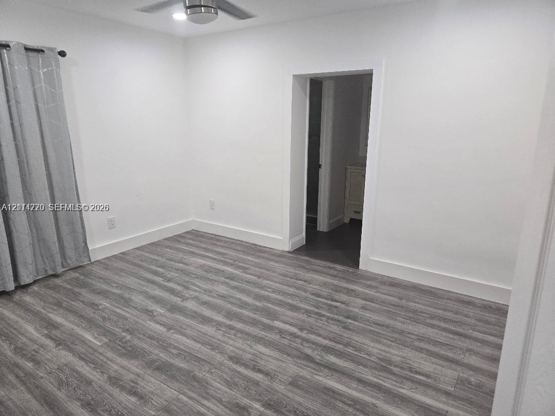 Interior space featuring wood-finish flooring, white walls, and a ceiling-mounted light fixture