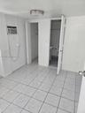 Room featuring neutral tile flooring, a wall-mounted cooling unit, ceiling-mounted lighting, and double-door closet storage