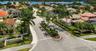 Aerial perspective of the Treasure Shores community entrance featuring a landscaped center median, palm tree-lined streets, and a waterfront position