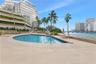 Waterfront swimming pool with stone-tiled deck, integrated spa, and mature palm landscaping