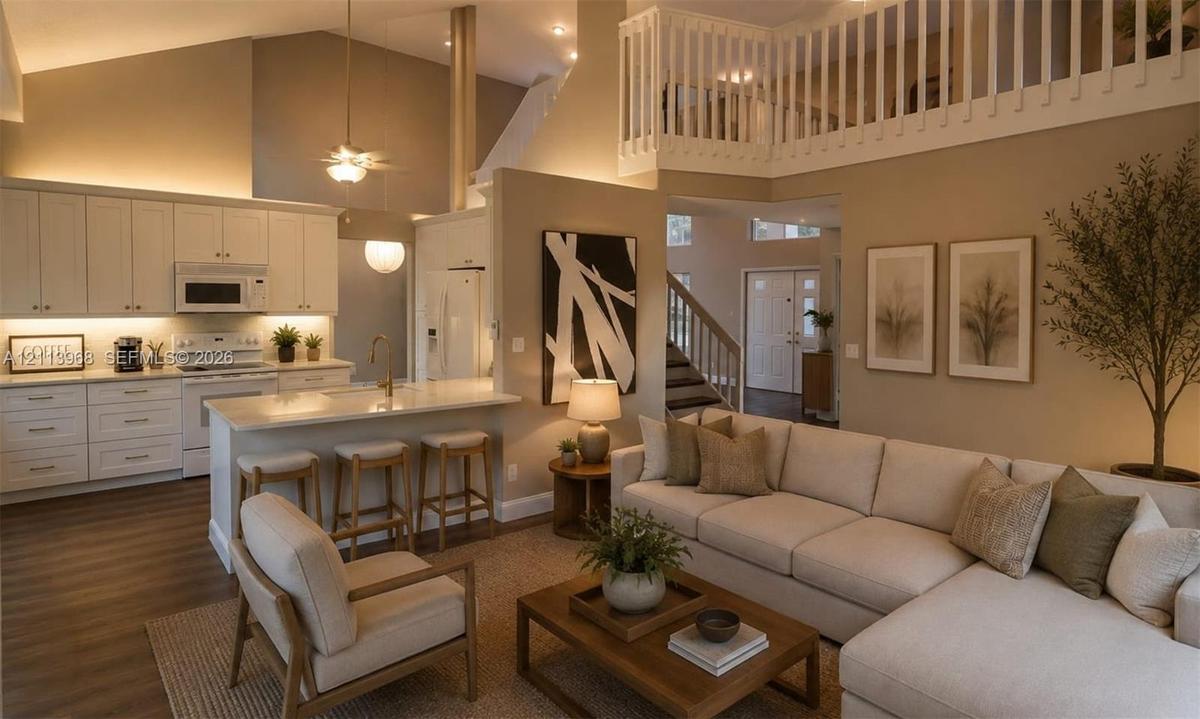 Vaulted ceilings with recessed lighting, kitchen featuring white shaker-style cabinetry, breakfast bar with stone-surfaced countertop, wood-finish flo