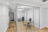 Enclosed office space featuring glass-panel walls, aluminum framing, recessed lighting, and wood-finish flooring