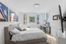 Bright room featuring wood-finish flooring, white walls, triple window configuration, and a square modern flush-mount ceiling light fixture