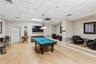 Multi-purpose space featuring wood-finish flooring, a raised platform seating area, a suspended multi-light fixture, and recessed lighting