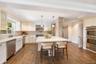 Kitchen featuring white cabinetry, an expansive central island with a solid surface countertop, wood-finish flooring, stainless steel built-in double 